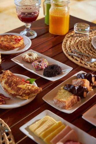 een houten tafel met borden met zoete deegwaren en drankjes bij Kauli Seadi Beach Hotel in São Miguel do Gostoso
