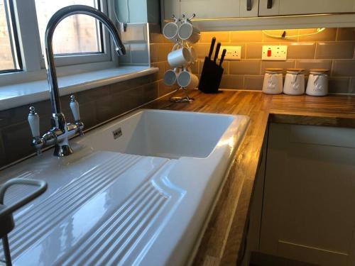 eine Küche mit einem weißen Waschbecken in der Küche in der Unterkunft Edinburgh Street Home - Beautiful House with Free Parking and Wifi, Equipped with comfy furnitures in Swindon