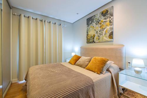 a bedroom with a bed and a painting on the wall at Vista do Vale! 400 metros da Rua Coberta - Acomoda até 4 hóspedes in Gramado