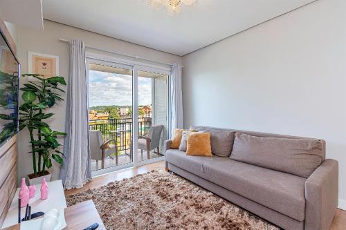 a living room with a couch and a balcony at Vista do Vale! 400 metros da Rua Coberta - Acomoda até 4 hóspedes in Gramado