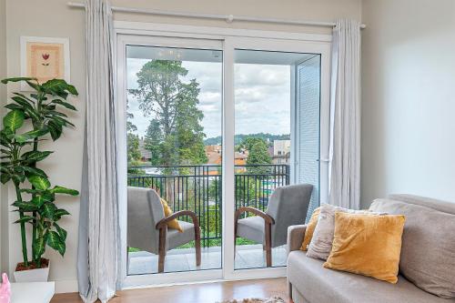 a living room with a sliding glass door to a balcony at Vista do Vale! 400 metros da Rua Coberta - Acomoda até 4 hóspedes in Gramado