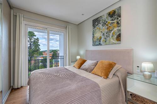 a bedroom with a bed and a large window at Vista do Vale! 400 metros da Rua Coberta - Acomoda até 4 hóspedes in Gramado
