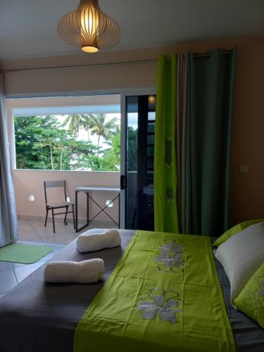 a bedroom with a large bed with a green blanket at Fare Tapu in Uturoa