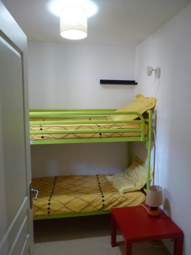 Zimmer mit 2 Etagenbetten und einem roten Tisch in der Unterkunft Le Caldarium - Classé 2 Etoiles - Thermes 10 mn - 6 pers in Avène