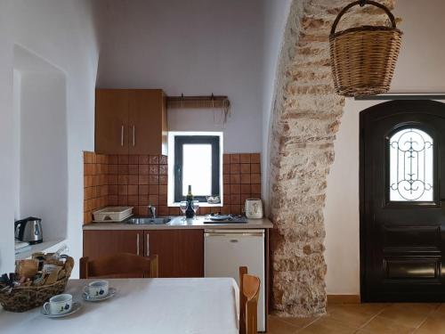 a kitchen with a table and a stone wall at The Old barrel houses in Kythira