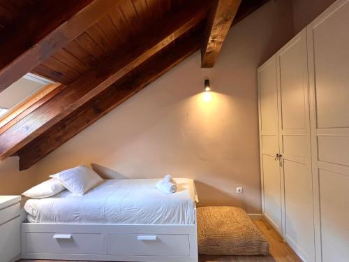 um quarto com uma cama branca num sótão em Dúplex La Roca em Espot