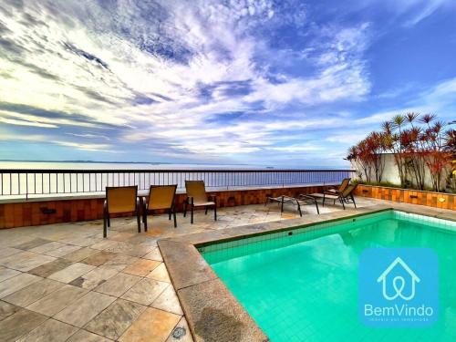 una piscina con sedie e vista sull'oceano di Apartamento completo com píer e acesso ao mar 4 a Salvador