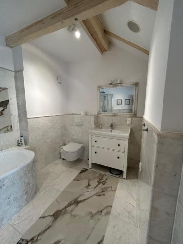 a bathroom with a tub and a sink and a mirror at Leśna Residence & SPA in Pisz
