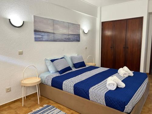 a bedroom with a large bed with blue and white sheets at Encantador apartamento com piscina in Costa da Caparica