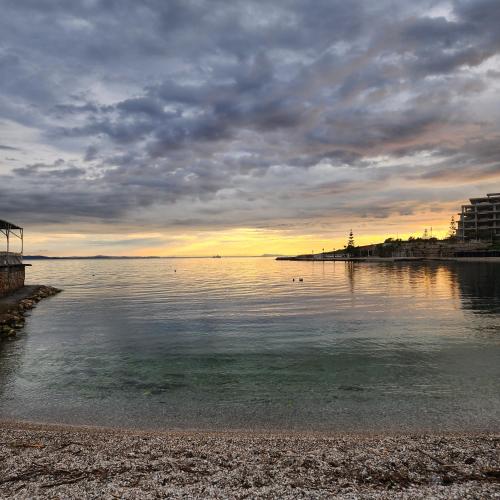a body of water with a cloudy sky and a beach at Amelie's Apartments & Beach Saranda in Sarandë