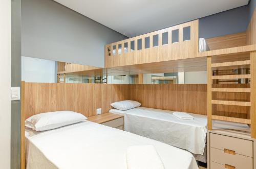 2 camas num quarto com beliches de madeira em Lifespace Curitiba - Duplex Incrível, 2 Quartos, varanda, 2 garagens Batel em Curitiba