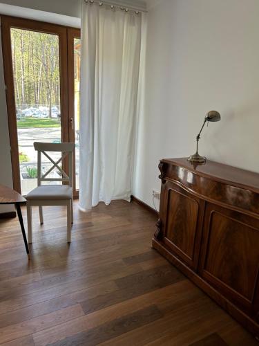 a living room with a dresser and a chair and a window at Leśna Residence & SPA in Pisz