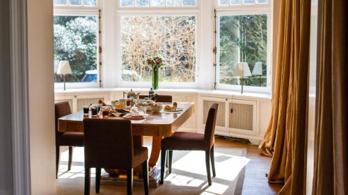 a dining room with a table and chairs and windows at Guest house La Maison Chantecler in Brussels