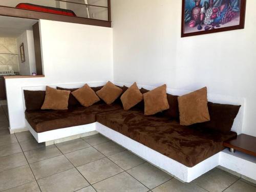 brązowa kanapa z poduszkami na ścianie w obiekcie Suite Misión Juriquilla #3 w mieście Juriquilla
