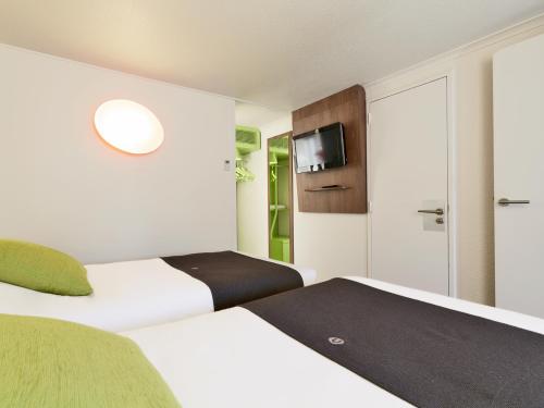 Cette chambre comprend 2 lits et une télévision. dans l'établissement Campanile Epinay sur Orge Savigny Sur Orge, à Épinay-sur-Orge