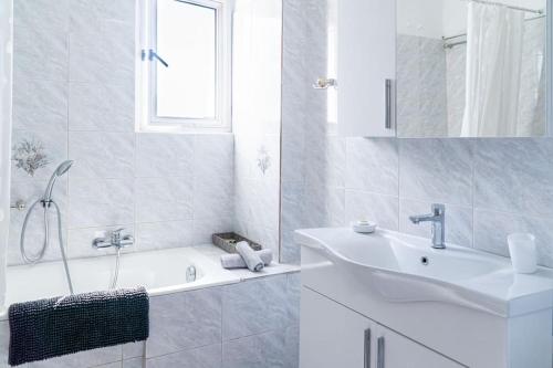 un bagno bianco con lavandino e vasca di Come and Sea apartment a Vlachata