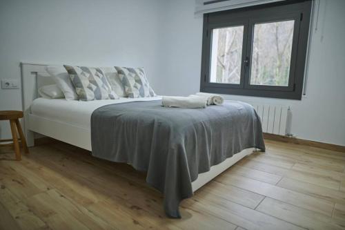 a bedroom with a bed with a blanket and a window at Can Mosqueroles casa en Castellfollit de la Roca in Girona