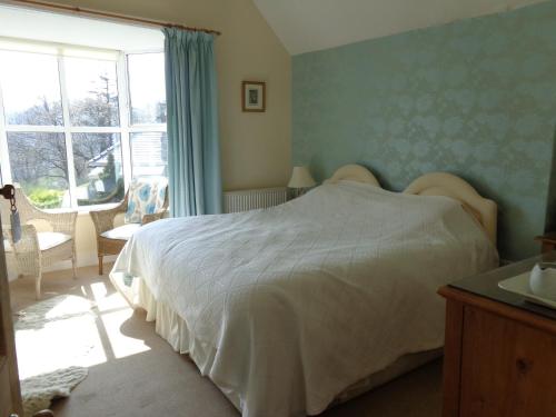 a bedroom with a white bed and a window at Staylittle Farm in Dolgellau