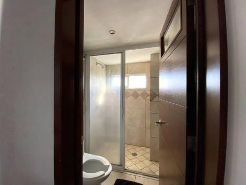 baño con aseo y puerta de ducha de cristal en Suite Misión Juriquilla #4, en Juriquilla