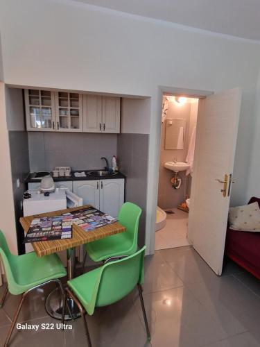a kitchen with a table and green chairs in a room at Apartments Katarina in Kotor