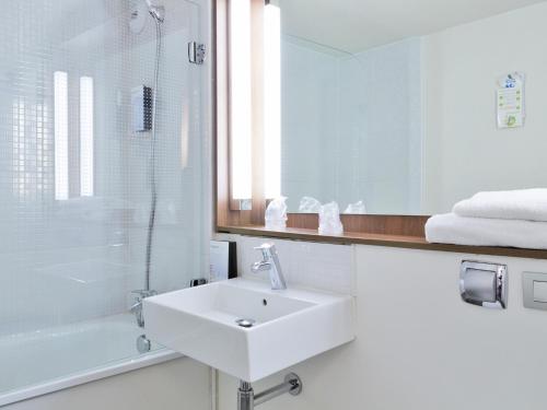 a white bathroom with a sink and a shower at Campanile Epinay sur Orge Savigny Sur Orge in Épinay-sur-Orge
