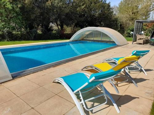 une paire de chaises assises à côté de la piscine dans l'établissement Très Jolie, à Saint-Martin-de-la-Coudre