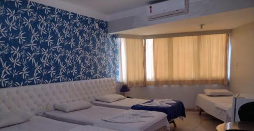 um quarto com duas camas e um papel de parede azul e branco em Feira Palace Hotel em Feira de Santana