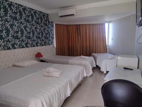 a hotel room with three beds and a window at Feira Palace Hotel in Feira de Santana