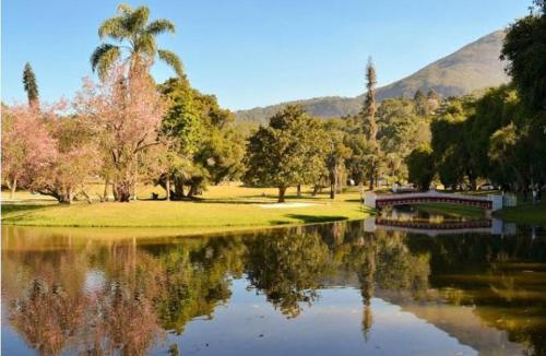einen Park mit einem Teich mit Bäumen und einer Brücke in der Unterkunft Pedra Do Imperador in Nova Friburgo