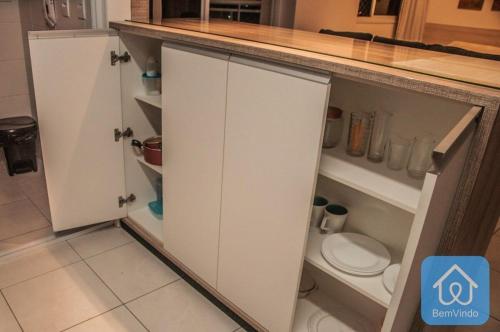 una cocina con armarios blancos y un aseo. en Apartamento completo ao lado do Salvador Shopping, en Salvador