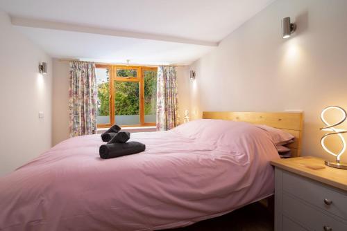 a bedroom with a pink bed with a teddy bear on it at Coachman's Quarters in Lynton