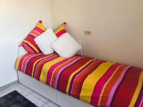 a bed with a colorful striped blanket and pillows at La vie à Ostende in Ostend