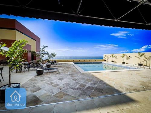 a view of a patio with a pool and the ocean at Apartamento aconchegante com píer e acesso ao Mar in Salvador