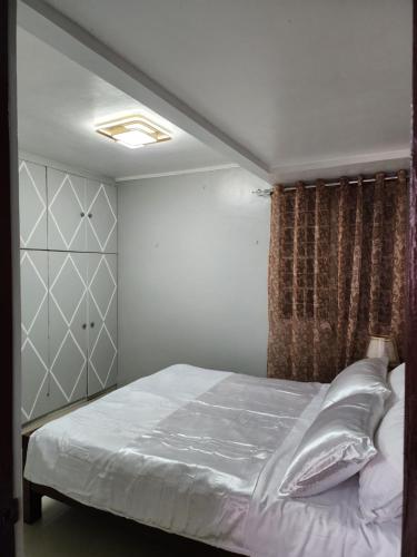 um quarto com uma cama com lençóis brancos e cortinas em LUXURY HOME em Cotabato