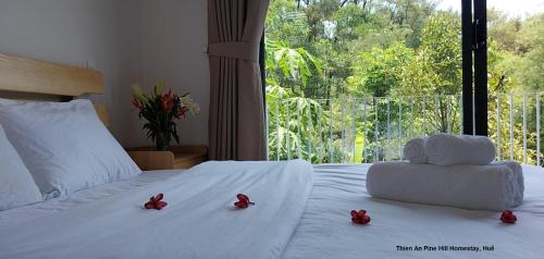 Una cama con flores rojas en ella con una ventana en Thien An Pine Hill Homestay Hue en Hue