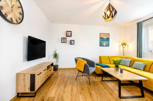 Dům u Mlejna : غرفة معيشة مع أريكة صفراء وتلفزيون