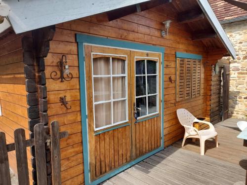 a cabin with a door and a chair on a deck at Chalet en bois en pleine Nature 4 personnes 3 lits Aventure Bien être et NAture Ferme Peyrot 64 in Vielleségure