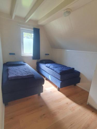 two beds in a small room with a window at Vakantiehuisje in Gramsbergen in Gramsbergen