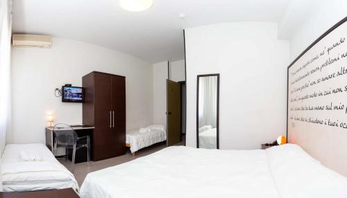 una camera con 2 letti, una scrivania e uno specchio di Hotel Solarium a Civitanova Marche