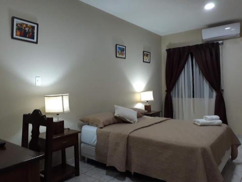 San José de Chiquitos的住宿－El Suto Apart Hotel，一间卧室配有一张床、一张桌子和两盏灯。