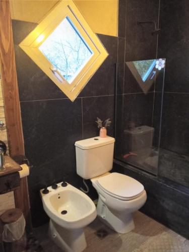 a bathroom with a toilet and a sink and a window at Cabaña Los Ulmos Bariloche in San Carlos de Bariloche