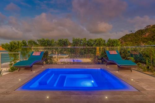 a blue swimming pool on a patio with two chairs at Villa La Vie en Bleu in Marigot