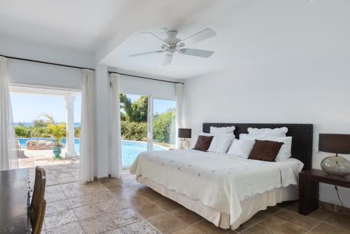 a white bedroom with a bed and a pool at Villa Lune de Miel in Marigot