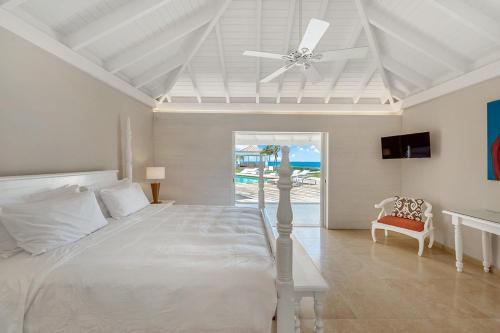 a bedroom with a white bed and a ceiling fan at Villa Casa Cervo in Marigot