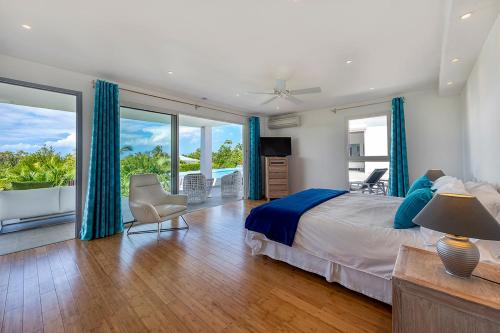 um quarto com uma cama com cortinas azuis e uma varanda em Villa Grand Palms em Les Terres Basses