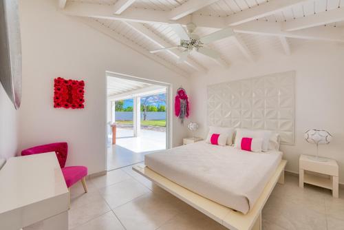 um quarto branco com uma cama grande e detalhes em rosa em Villa Plum Bay em Marigot