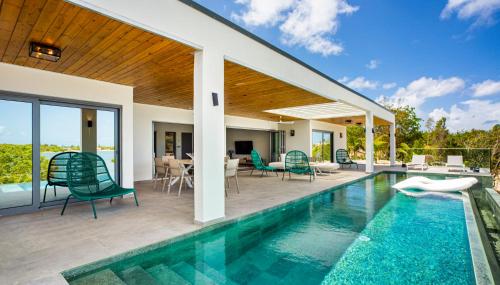 a house with a swimming pool and a patio at Villa Enjoy in Les Terres Basses
