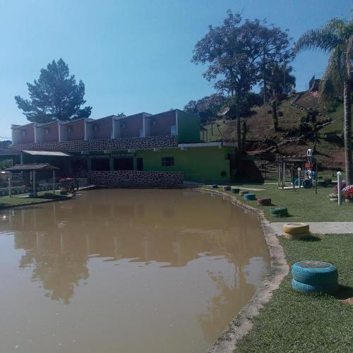 una piscina de agua embarrada frente a un edificio en Pesqueiro Restaurante e Pousada Pingo de Ouro, en Piedade
