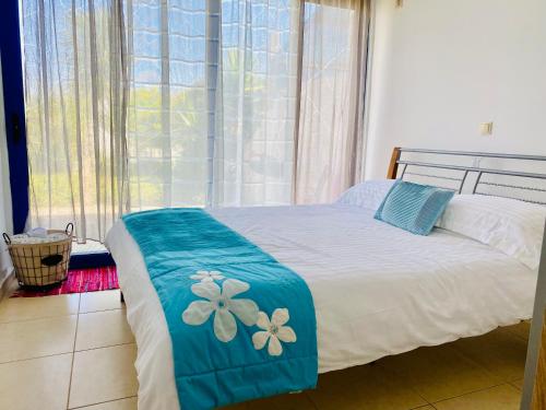 Un dormitorio con una cama con sábanas azules y blancas y una ventana en The Citrus House, en Kalavárda
