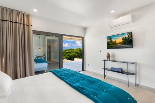 a bedroom with a bed and a sliding glass door at Villa Wellness in Baie Longue